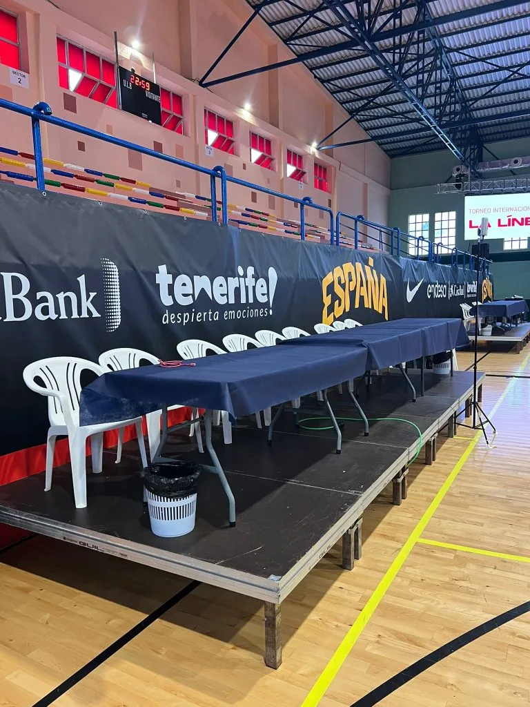 Mesa de anotadores sobre tarima enmoquetada junto a la pista