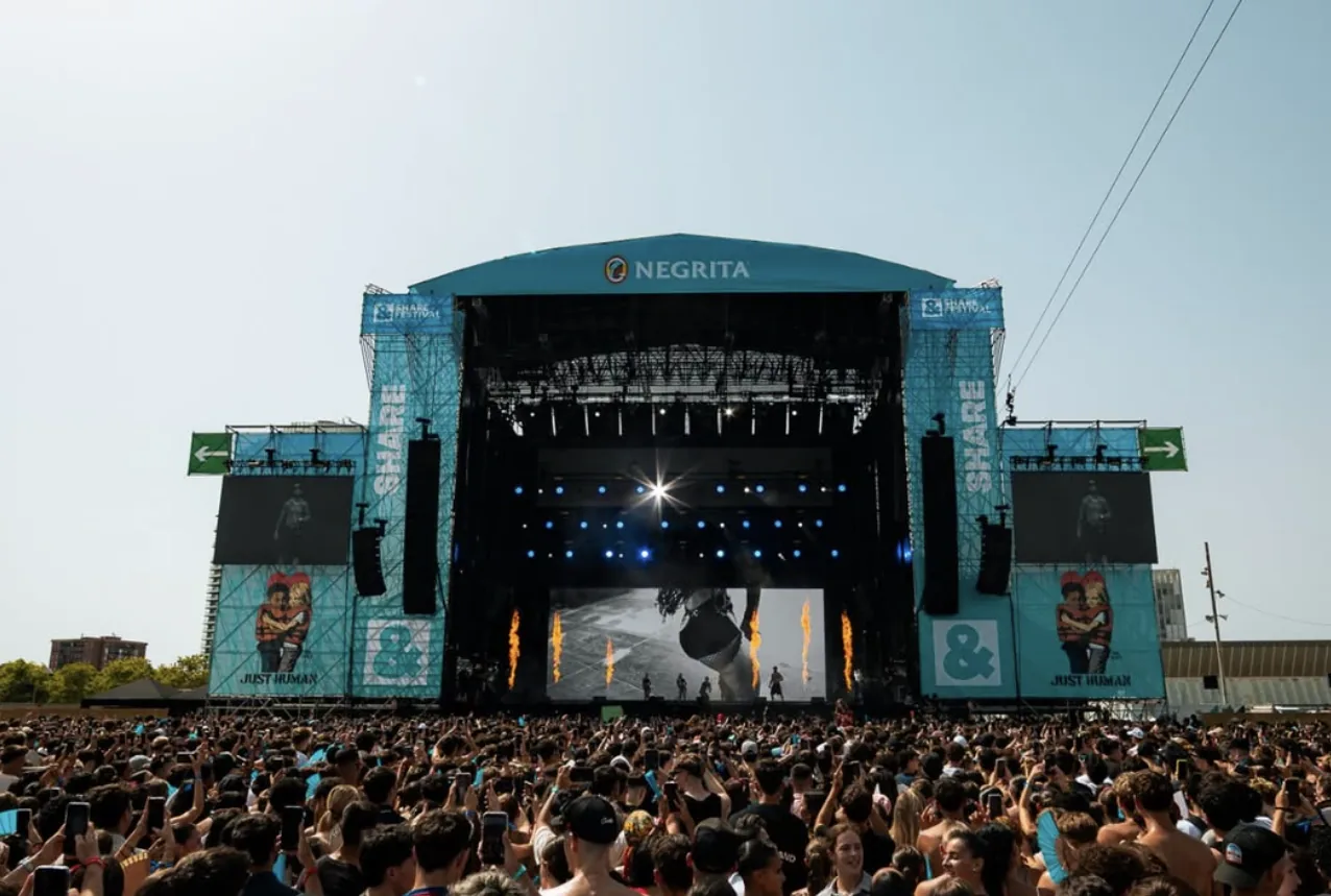 Escenario de festival con pantallas LED y público durante el concierto